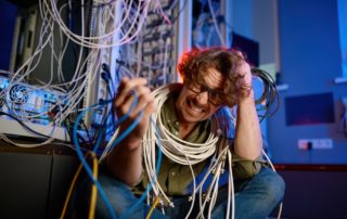 computer technician tangled in unorganized cables.